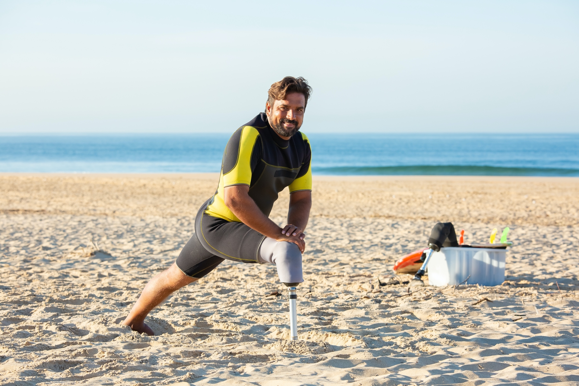 A man with one leg does a lunge using his prosthetic leg on the beach