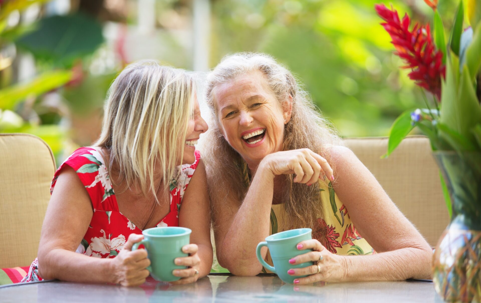 Two women share a laugh over cups of coffee