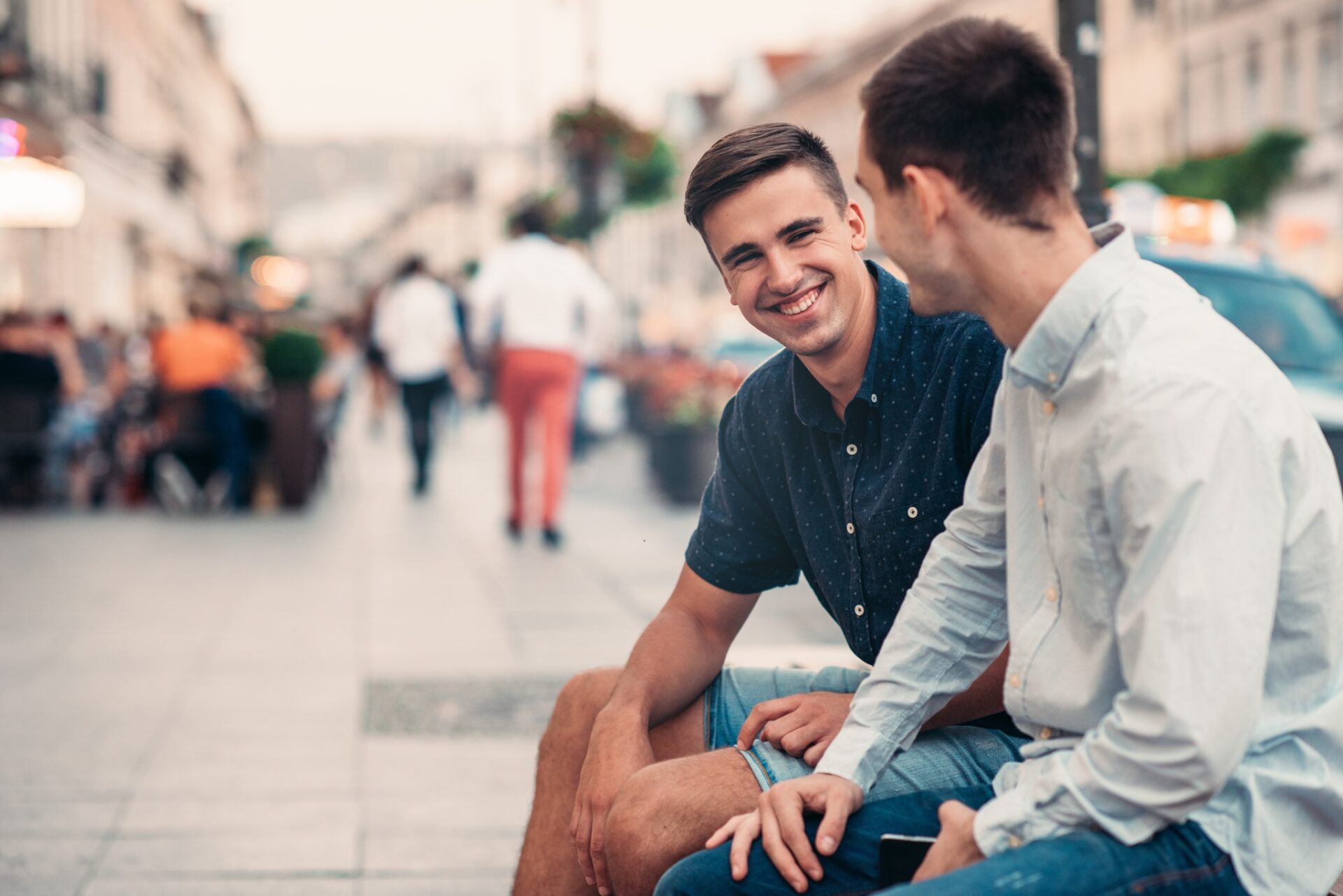 Two young men have a conversation while sitting outside